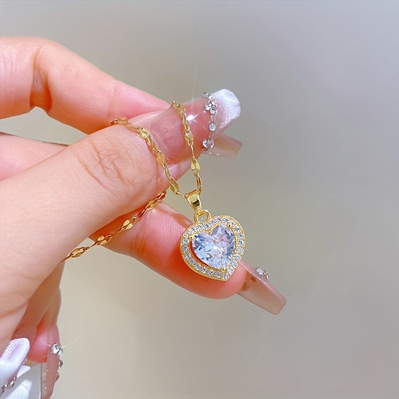 Un collier avec pendentif en zircone synthétique en forme de cœur scintillante. Cette pièce intemporelle et adaptable pour femmes est dotée d'une chaîne en acier inoxydable plaqué or, ce qui en fait un cadeau de bijoux idéal pour les anniversaires, les fêtes de Noël et la Saint-Valentin.