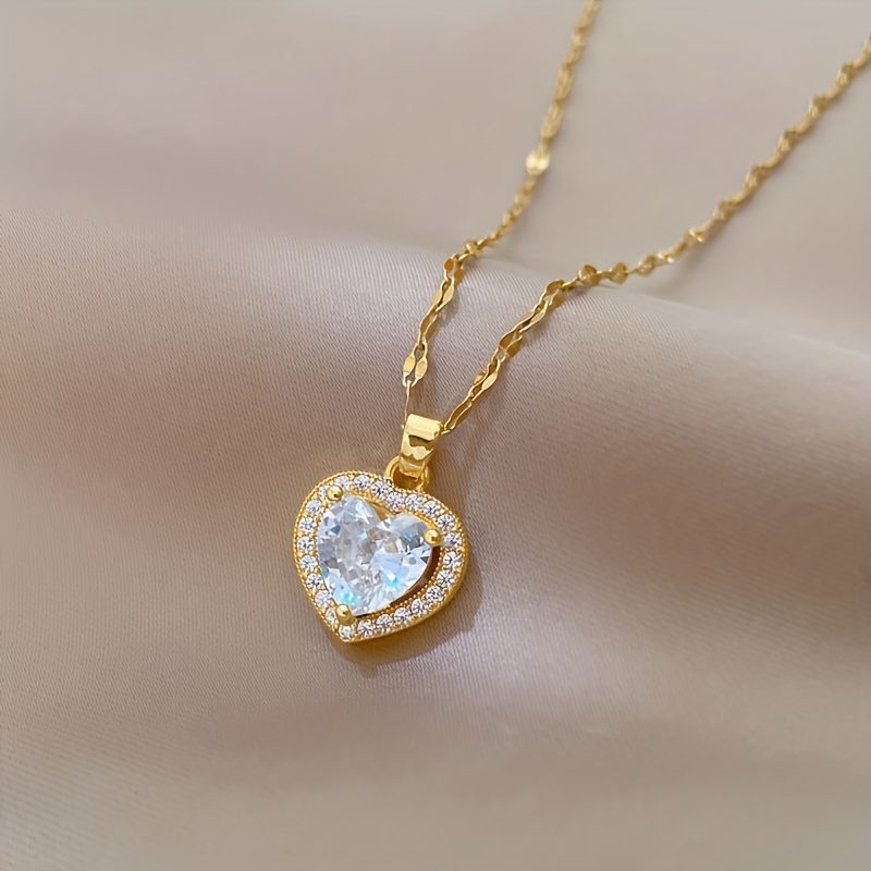 Un collier avec pendentif en zircone synthétique en forme de cœur scintillante. Cette pièce intemporelle et adaptable pour femmes est dotée d'une chaîne en acier inoxydable plaqué or, ce qui en fait un cadeau de bijoux idéal pour les anniversaires, les fêtes de Noël et la Saint-Valentin.