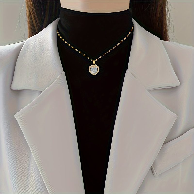 Un collier avec pendentif en zircone synthétique en forme de cœur scintillante. Cette pièce intemporelle et adaptable pour femmes est dotée d'une chaîne en acier inoxydable plaqué or, ce qui en fait un cadeau de bijoux idéal pour les anniversaires, les fêtes de Noël et la Saint-Valentin.