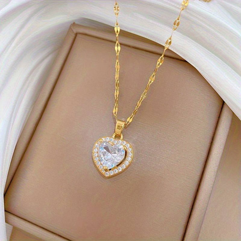 Un collier avec pendentif en zircone synthétique en forme de cœur scintillante. Cette pièce intemporelle et adaptable pour femmes est dotée d'une chaîne en acier inoxydable plaqué or, ce qui en fait un cadeau de bijoux idéal pour les anniversaires, les fêtes de Noël et la Saint-Valentin.